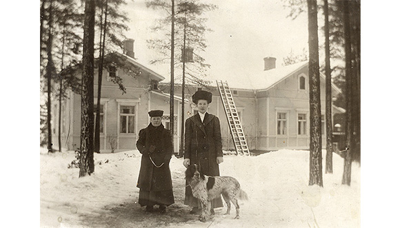 Talvinen näkymä Voikkaan tehtaan isännöitsijän asunnon Kuukerpallin edustalta 1910-luvun alussa. Oikealla Hilma Nieminen, joka oli tuolloin Norrmanilla sisäkkönä, vierellään rouva Mari Norrman sekä isännöitsijän ”Heiju”-setteri.