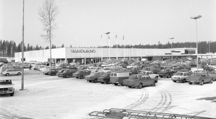 Etualalla valtava määrä autoja pysäköitynä Sokos-Marketin pysäköintialueelle. Niiden takana Sokos-Marketin rakennus sekä Shellin huoltoasema. Maassa lunta.